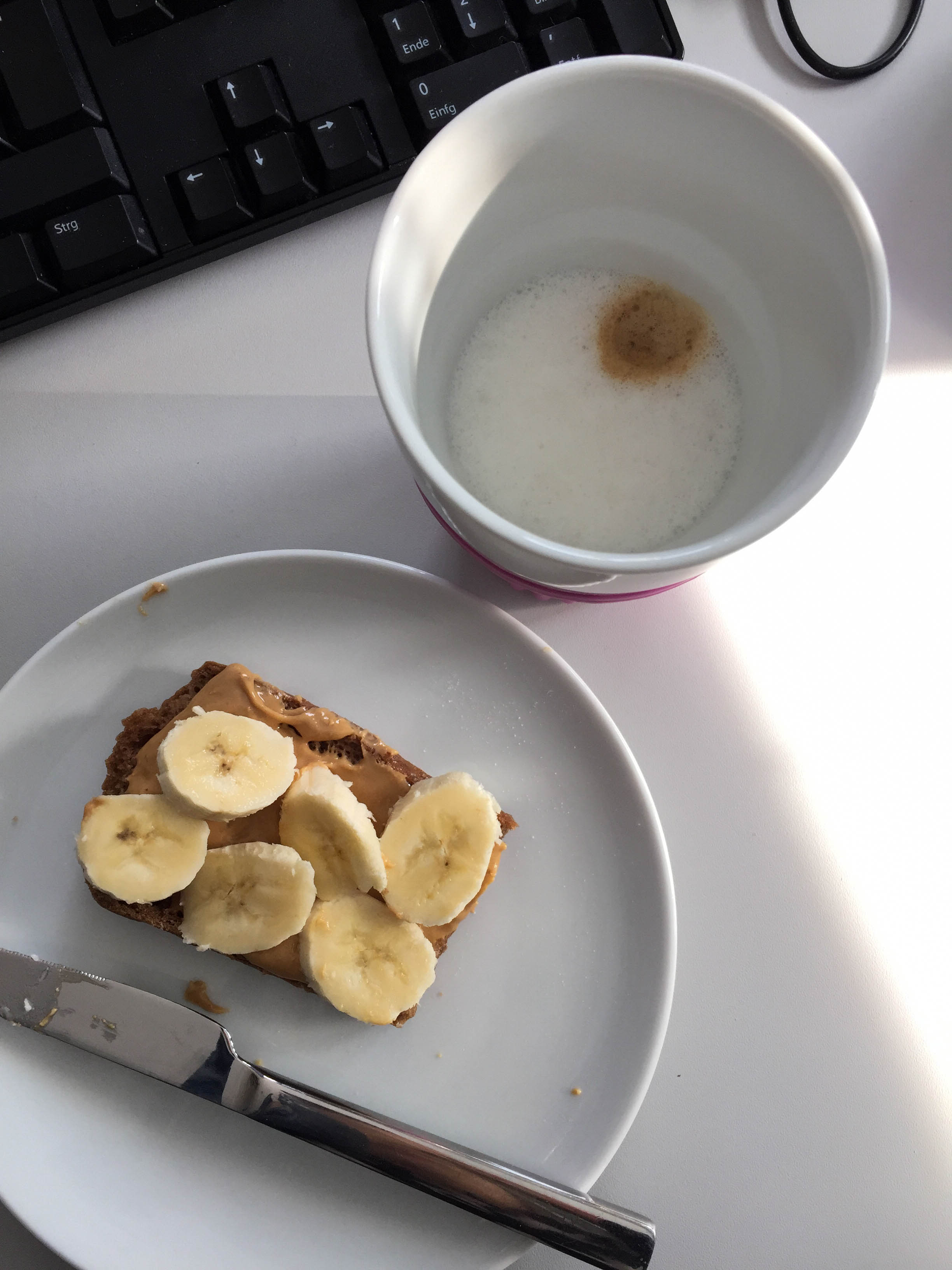 Bürofrühstück - Kaffee mit Mandelmilch, dazu ein Toast mit Cashewbutter und Banane. 